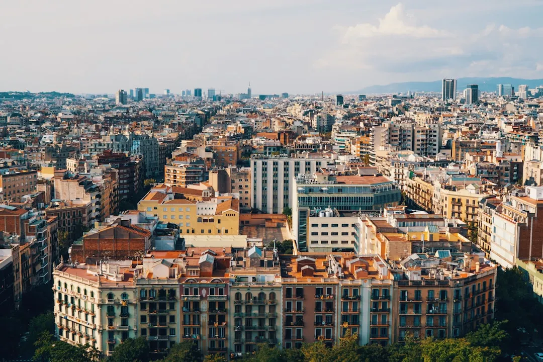 A panoramic view of Barcelona, showcasing the city's distinctive architecture and vibrant urban landscape under a partly cloudy sky.