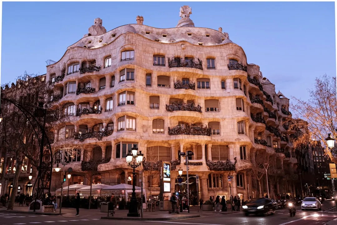 A view of Casa Milà, also known as La Pedrera, in Barcelona, showcasing its unique undulating stone facade and artistic balconies at dusk.