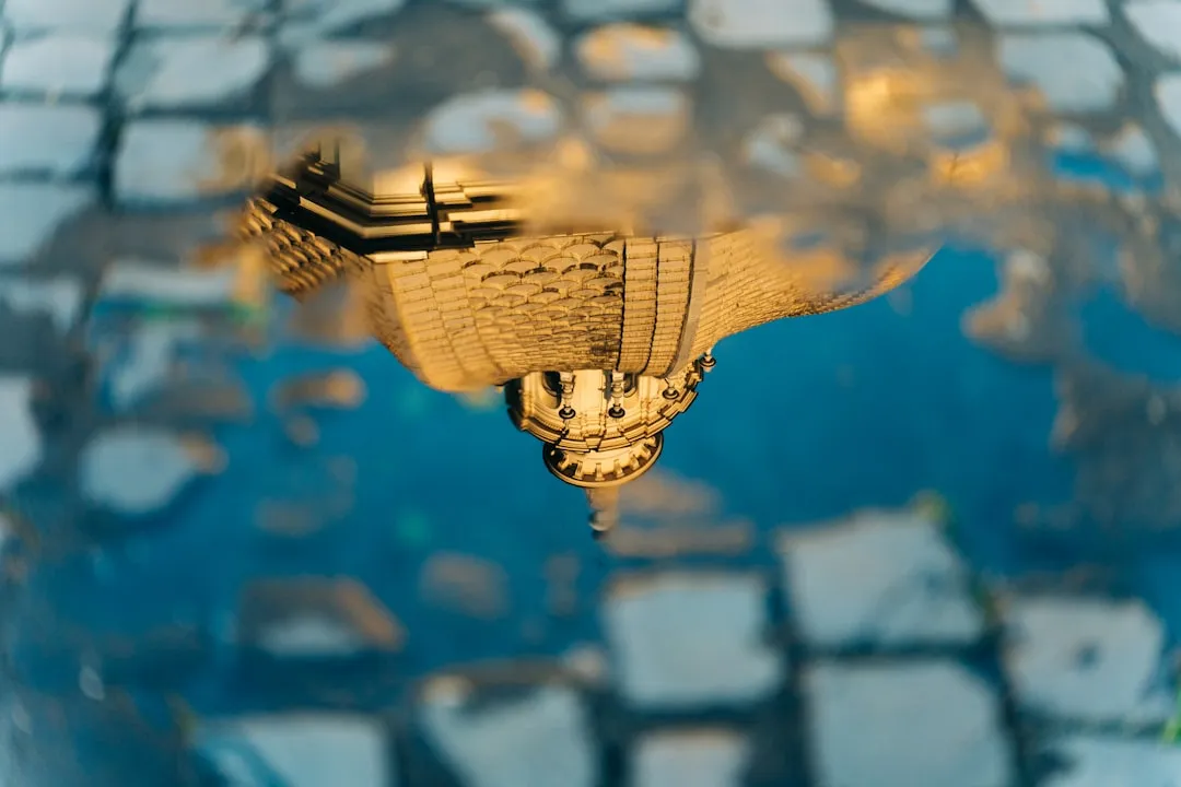 Upside-down reflection of a classical building in water with golden sunset sky, creating a surreal mirrored effect